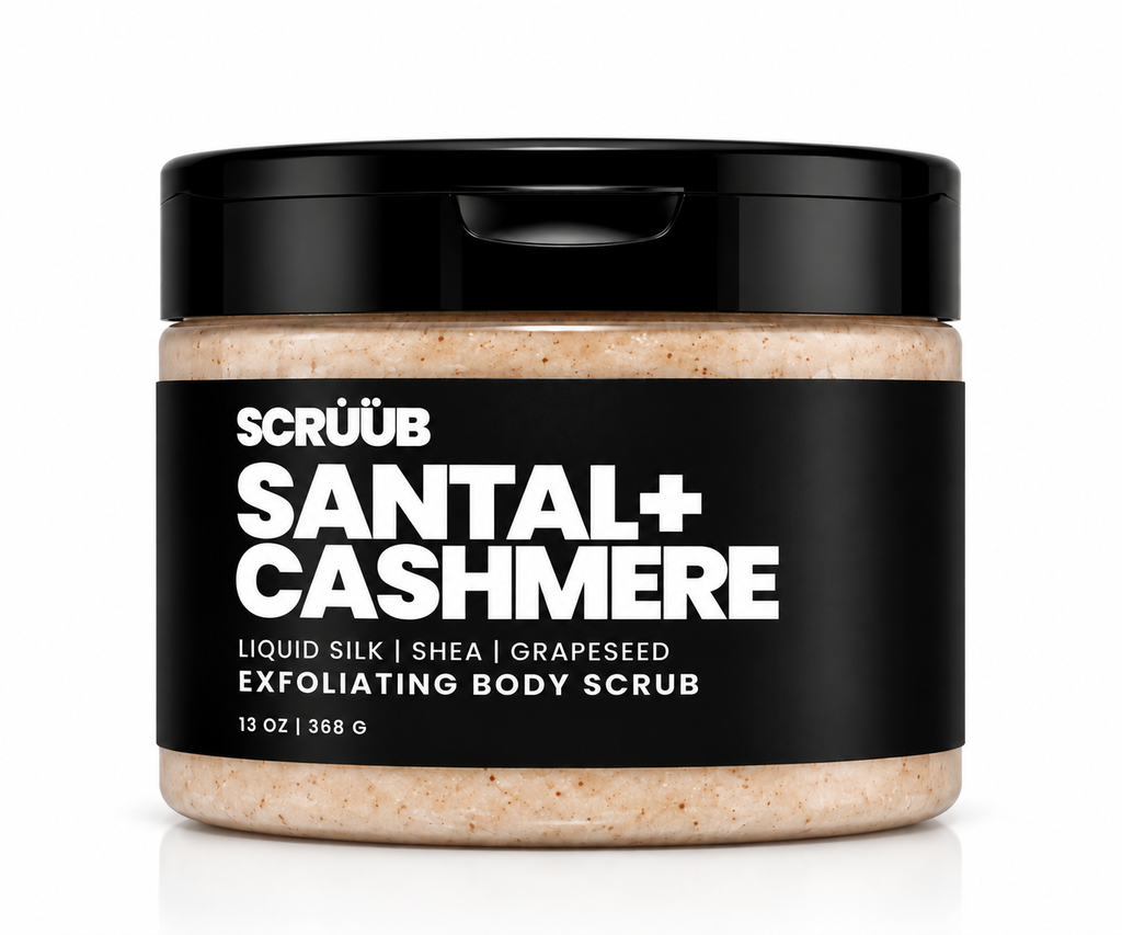 A jar of Scrüub Santal+ Cashmere exfoliating body scrub, featuring a black lid and a black label with white text, showing the beige scrub inside. The product is photographed on a clean white background with a soft reflection.