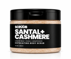 A jar of Scrüub Santal+ Cashmere exfoliating body scrub, featuring a black lid and a black label with white text, showing the beige scrub inside. The product is photographed on a clean white background with a soft reflection.